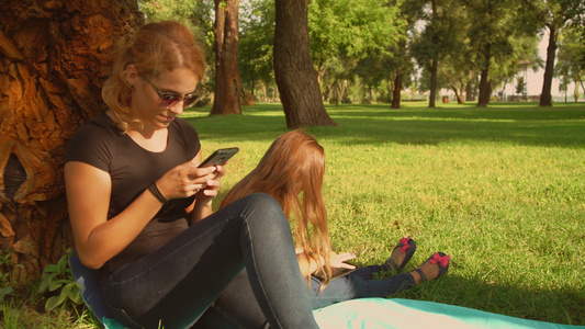 母亲和女儿在公园里使用小工具视频
