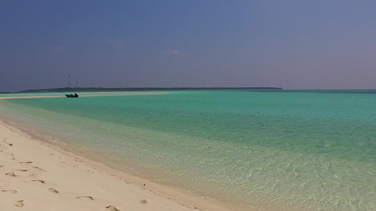 以蓝水和接近冲浪的白沙背景为蓝水绘制的宁静海滩野生视频