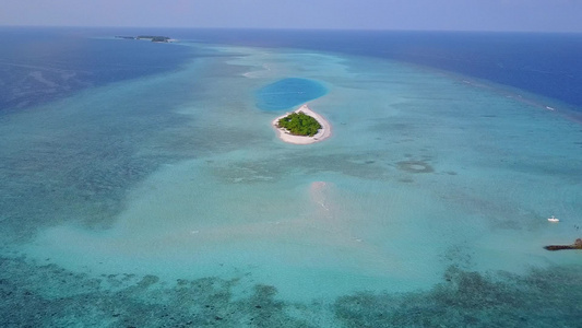 沿蓝海和沙滩附近白沙沙底的宁静海岸线海滩航行的宽角视频