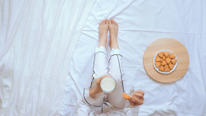 穿着白睡衣的女性喝牛奶和吃饼干坐在床上12秒视频