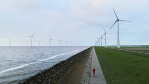 海边发电的风车下骑行经过的女孩20秒视频