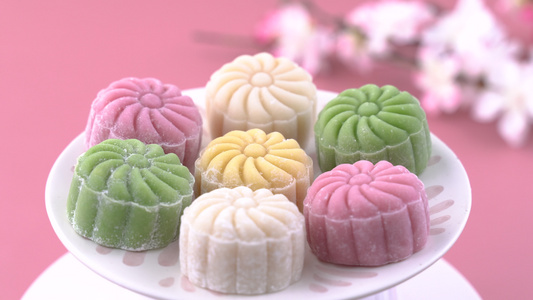 彩色雪皮月饼甜雪月饼中秋节传统咸味甜点淡粉色背景特写视频