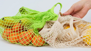 手将一个可再使用的纺织绳袋装在白色表面的成熟黄10秒视频