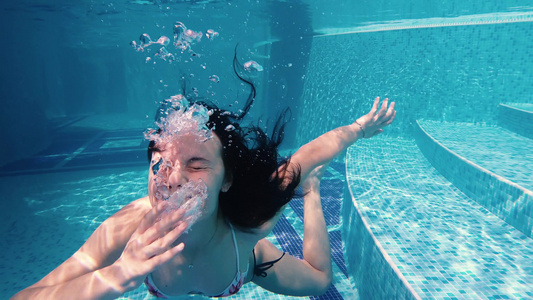 女孩在水下制造面孔阴暗和泡泡视频