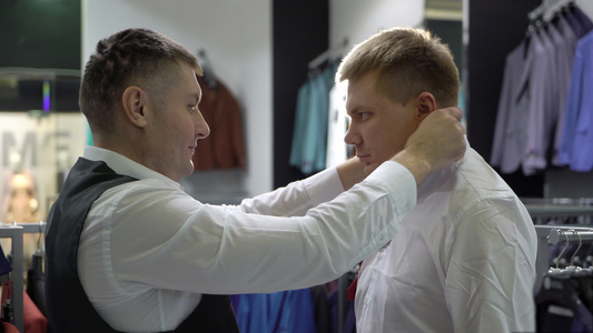 购物和时装概念青年男子在商场选择和试穿夹克视频
