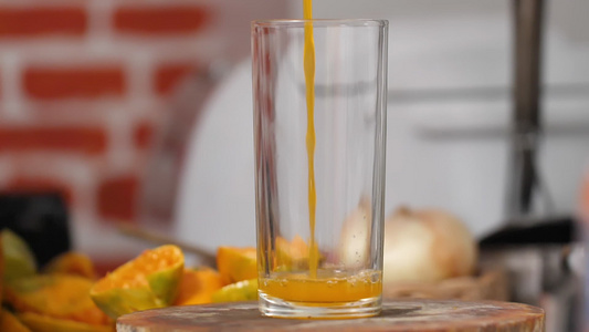 将橙汁倒到厨房的剪切板上一个清晰的玻璃杯里视频