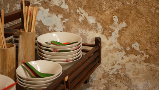 木制架子和各种亚裔的餐具在厨房中倒塌的墙壁旁边挂着视频