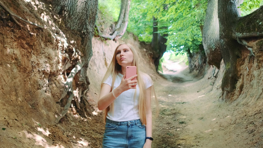 金发碧眼的年轻金发女青年在魔法根峡谷用智能手机拍照视频