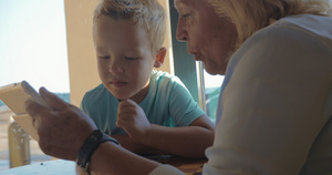 外婆和外孙坐在一起教他如何使用平板电脑27秒视频