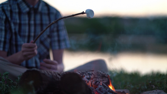 年轻游客在露营附近的营火上烤棉花糖视频