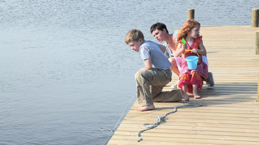 母亲和孩子们坐在湖边的码头上视频
