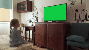白种人金发小女孩在卧室的床边观看带有绿色屏幕色度键17秒视频
