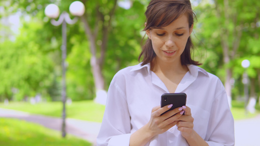 在公园使用手机进行在线聊天的千百年女孩视频