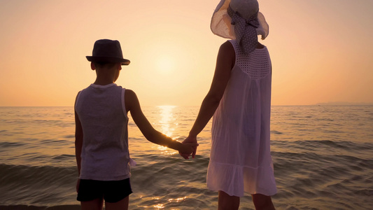 带着帽子站在日落海滩上的母亲和儿子Standicam视频