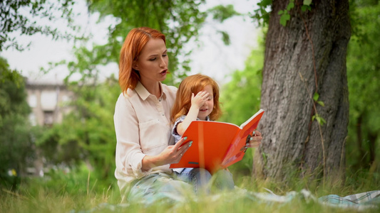 母亲和女孩坐在树下看书视频