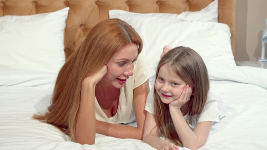 母亲和女儿对着镜头微笑躺在床上一起躺在床上视频