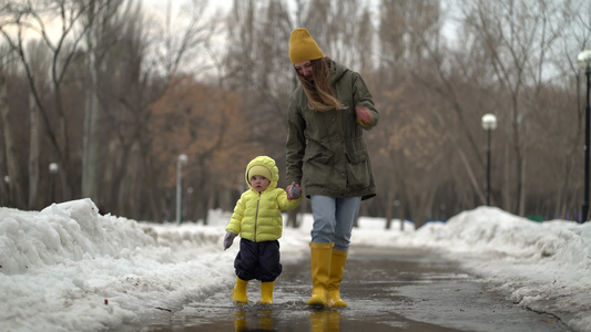 母亲和女儿穿着黄色橡胶靴子在水坑里行走视频