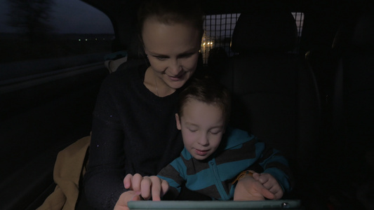夜间乘车时玩触摸垫母亲和儿子玩视频