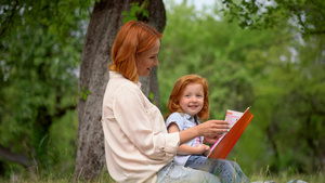 母亲和女孩坐在树下看书8秒视频