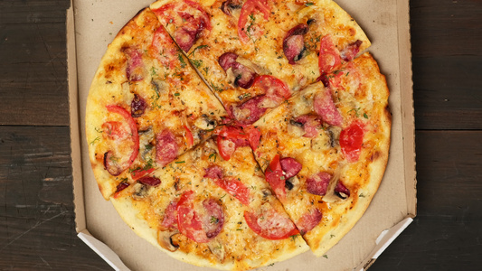 用香肠西红柿和奶酪在白纸板盒中烤成圆环披萨女性手打开视频
