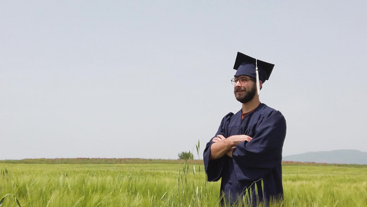 独自在绿田里毕业的男人把蓝色的帽子扔到空中视频