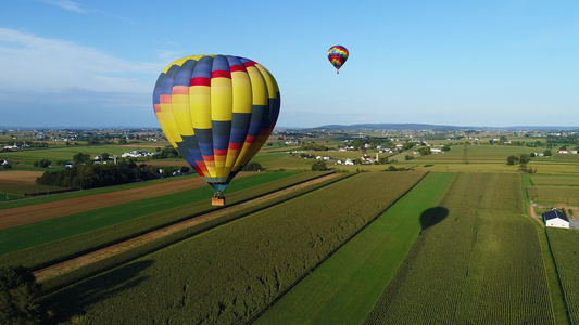 在阳光明媚的夏日庆典期间一个热空气气球在农场上漂浮视频