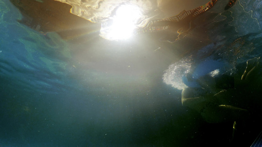 小男孩在水下观察日落的太阳学习游泳时用橡皮环在池子视频