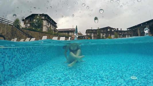 快乐的女孩在雨天雨滴打到水面时享受游泳池gopro视频
