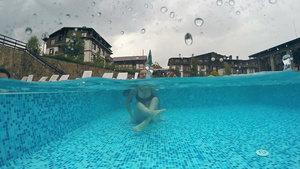 女孩在下雨的游泳池里游泳30秒视频