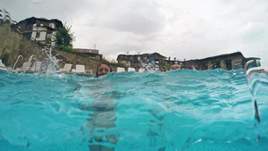 两个快乐的姑娘笑着在雨天中在游泳池里享受淋浴半水下30秒视频