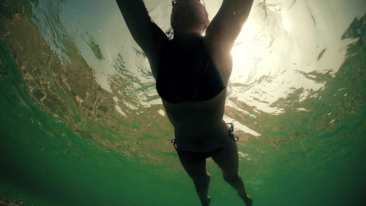 迷人的年轻女子游在美丽的英美天然海洋中日落阳光照耀视频