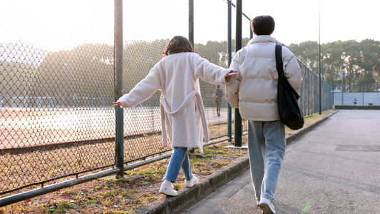 行走在操场边的男同学和女同学视频