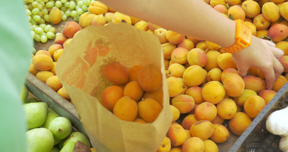 妇女在市场上选择成熟的杏子视频