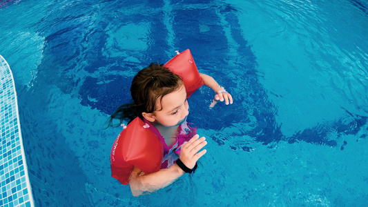 快乐的小女孩充满了充气的臂带在游泳池中放松微笑视频