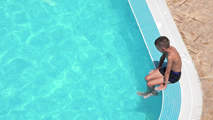 坐在泳池边缘的悲伤男孩双腿在水中8秒视频