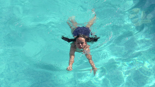 年轻女子在游泳池游泳空中旅行视频