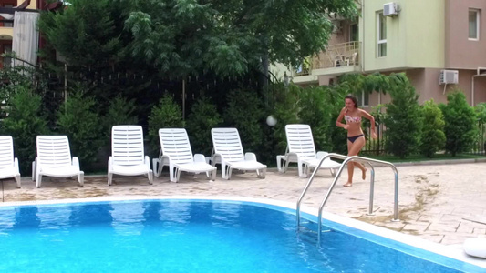 女孩在蓝游泳池里跑步跳跃慢动作视频