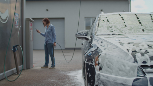 30多岁的年轻女性使用移动应用程序支付自助洗车费用视频
