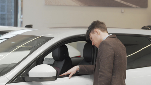 一名成熟男子在经销商出售的一辆新车里看着一辆新车视频