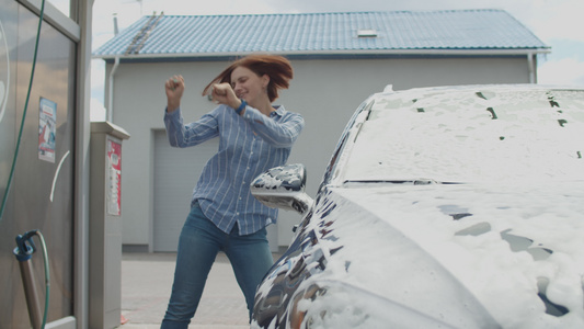 年轻成年女性乐于用外面的泡沫和水洗她的车而她却在外边视频