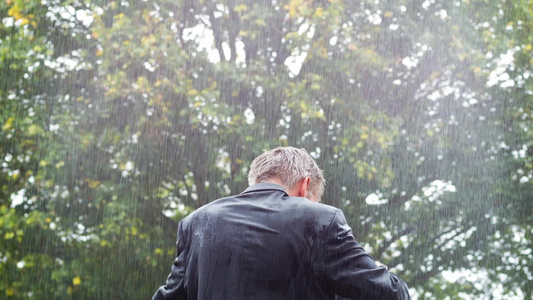 一名商人在雨中躲在他的包下看他的后排风景视频