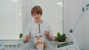 美容师在美容院给女人脸上涂奶油面罩17秒视频