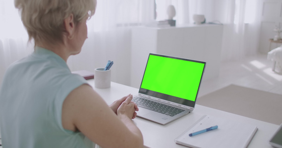 金发金发女人通过视频电话在线沟通查看笔记本电脑的绿色视频