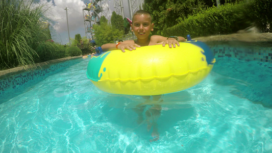 快乐的男孩享受水公园橡胶游泳在懒惰的河里游视频