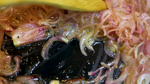 红洋葱切块煎用木勺在热油中翻动不健康的快速配菜的概念8秒视频