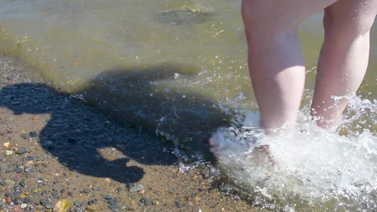 一名渡假者沿着岸边走在踢水上制造喷雾视频