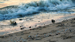 海面日落沙滩上留下塑料玻璃和废物海浪将它们吹入海中11秒视频