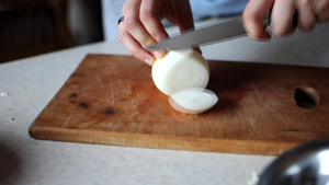 女孩把洋葱切成两半用木板上的一把尖刀把它切成小块在20秒视频