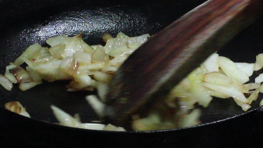 洋葱在黑煎锅里炒熟烤焦橄榄油的洋葱视频