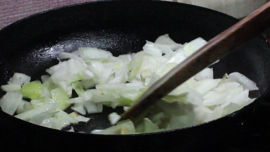 洋葱在黑煎锅里炒熟烤焦橄榄油的洋葱视频